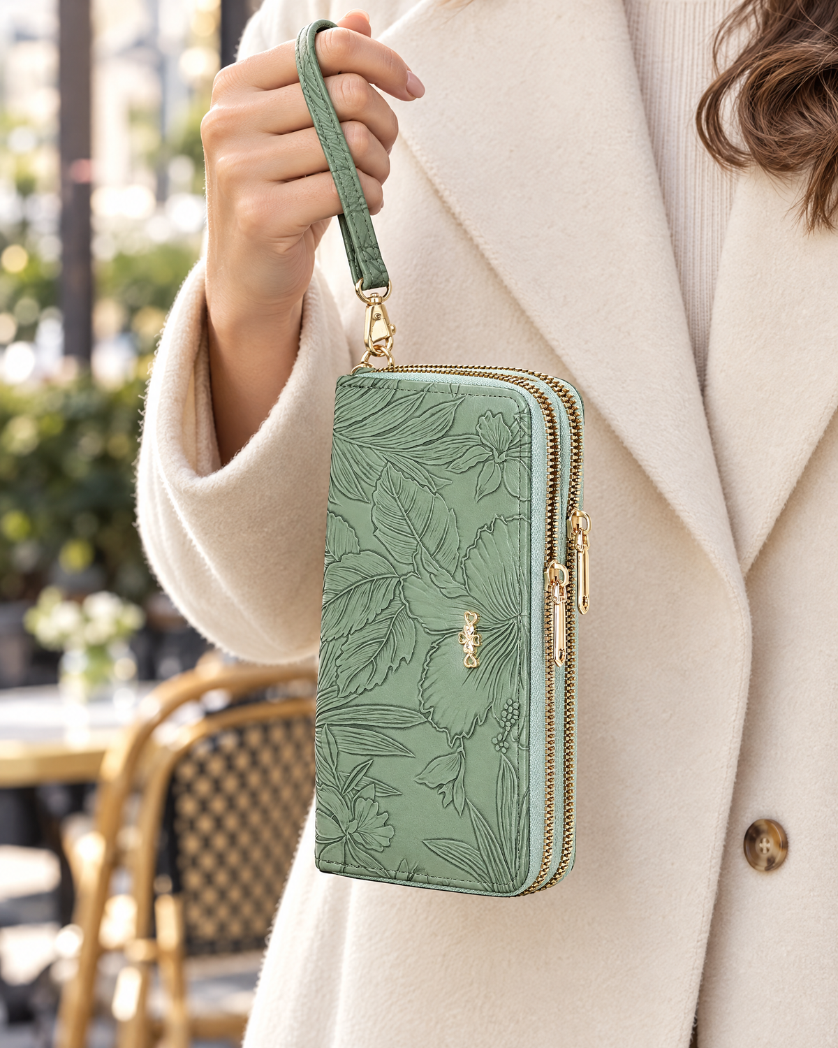 Hand holding green embossed wristlet wallet